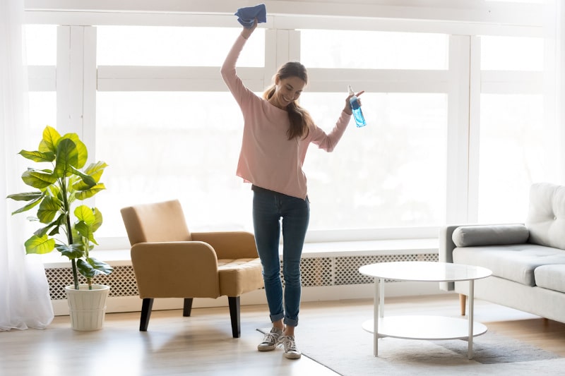 Woman holding cleaning products in living room