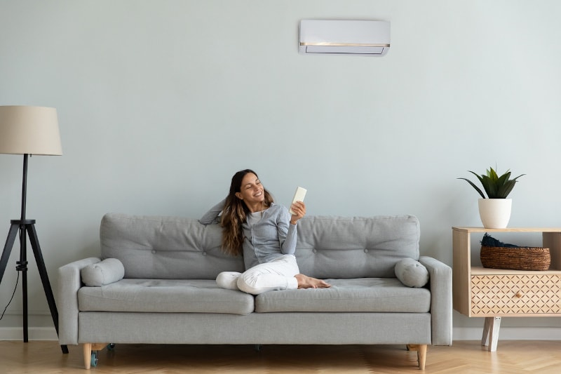 Woman Controlling Ductless AC on Couch